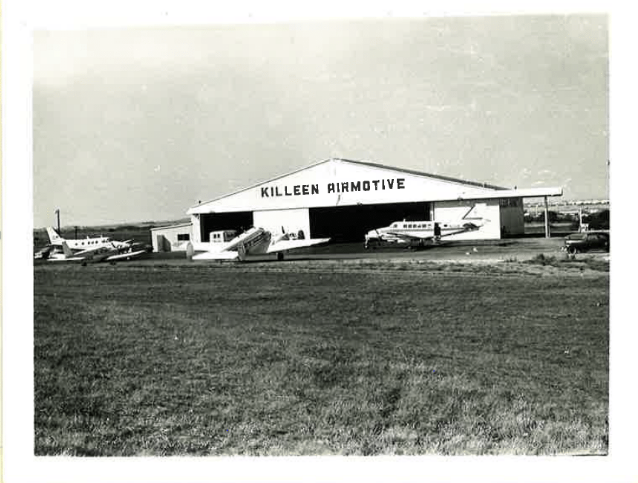 Historic black and white photo of Killeen Airmotive hangar in 1967 with four aircraft sitting on the ramp